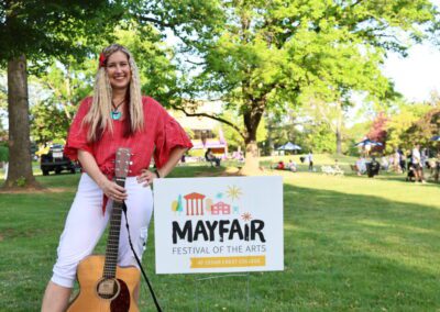 Stacy Gabel holding a guitar in front of Mayfair sign.