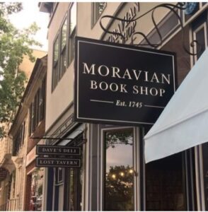 A sign for the moravian book shop on a city street.